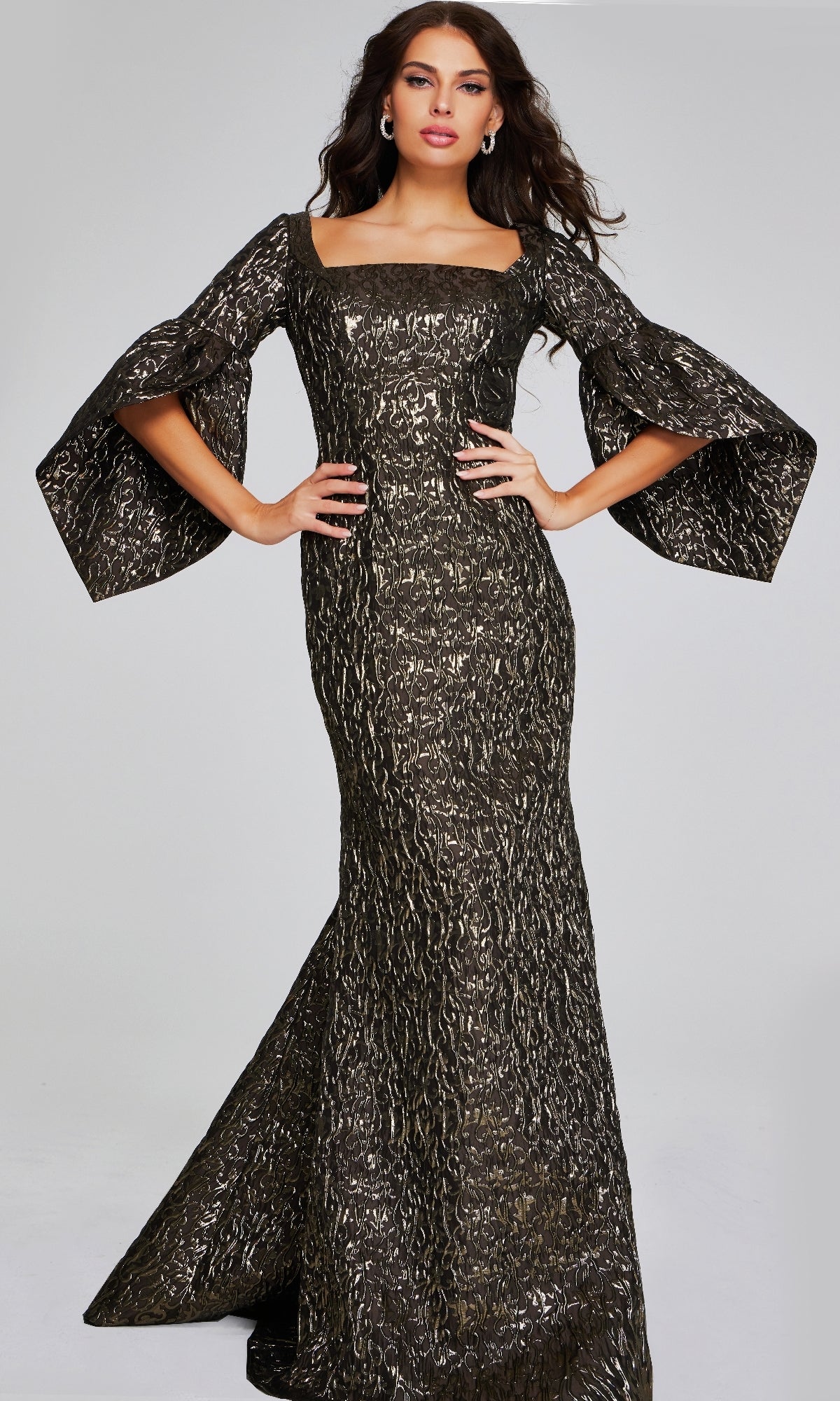 A woman poses against a plain light background in the Jovani 39080 long formal dress—featuring a fitted, metallic-textured mermaid silhouette, wide flared sleeves, square neckline, and floor-length hem.