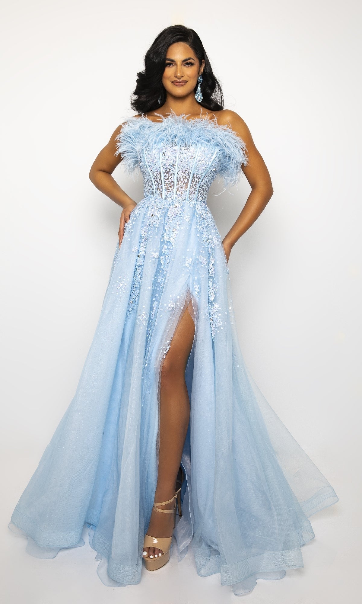 Woman wearing the Ava Presley 39232 Feather Long Prom Ball Gown in light blue with lace details and a high slit, paired with nude high heels, standing against a plain white background.