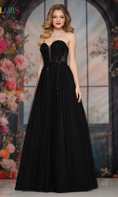 A woman in the Strapless Long Corset Prom Dress: Colors Dress 3923 stands before a floral and arched window backdrop.
