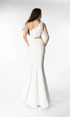 A woman stands with her back to the camera against a plain white background, wearing the Ava Presley 39247—a white, one-shoulder long prom dress with floral texture and a fitted skirt.