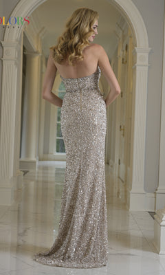A woman in the Colors Dress 3939 long prom dress, featuring a strapless sequined design, stands in a marble hallway with her back to the camera.