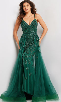 A woman models the Long Prom Dress 39434 by Jovani—a deep green formal gown with thin straps, beaded details, floral embellishments, and a flowing tulle A-line overskirt—posed against a plain background.