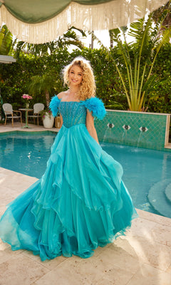 A woman with curly blonde hair models the Ava Presley 39553 feather long prom ball gown—bright blue, off-the-shoulder with feathered sleeves and a beaded bodice—by a pool in a tropical outdoor setting.