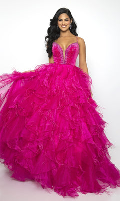 A woman smiles at the camera in the Ava Presley 39554, a bright pink long ruffled prom ball gown with a deep V-neckline and beaded bodice, standing against a plain white background.