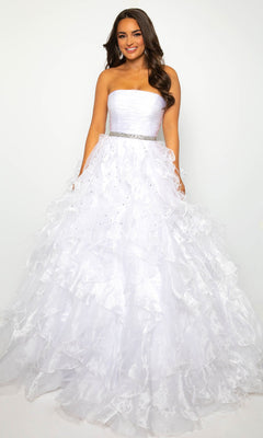 A woman smiles at the camera in the Strapless Ruffle Prom Gown: Ava Presley 39555, featuring a jeweled waistband and ruffled A-line skirt, standing against a plain white background.
