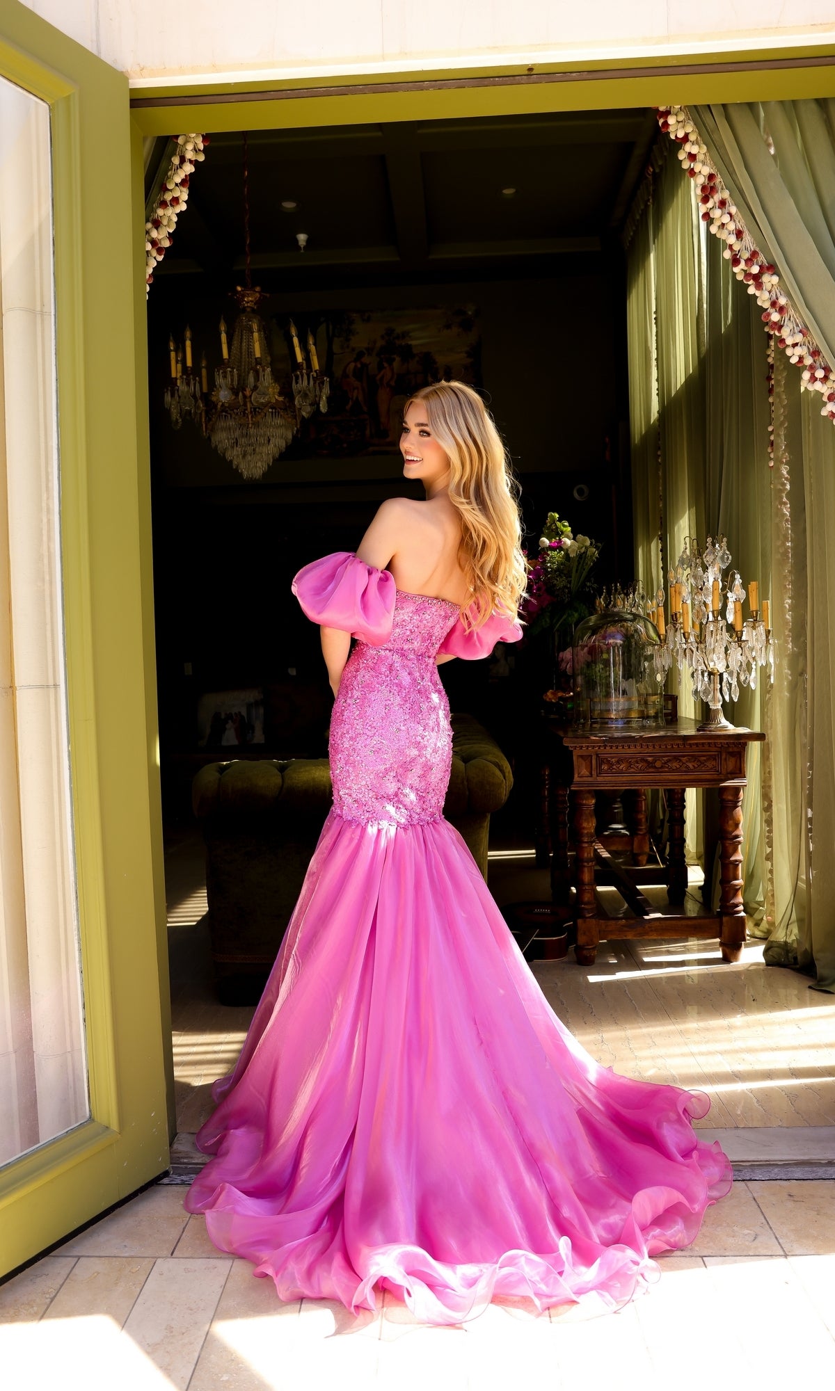 A woman in the Ava Presley 39570 puff-sleeve long prom dress stands in a doorway, looking over her shoulder.