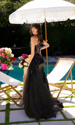 Wearing the Ava Presley 39572 one-shoulder sequin prom gown, a woman stands by a pool holding her dress, with deck chairs, flowers, and a white umbrella in the background.