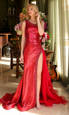 A woman wearing the Ava Presley 39572 one-shoulder sequin prom gown in shiny red with a high slit stands indoors by a table with flower arrangements and a guitar in the background.