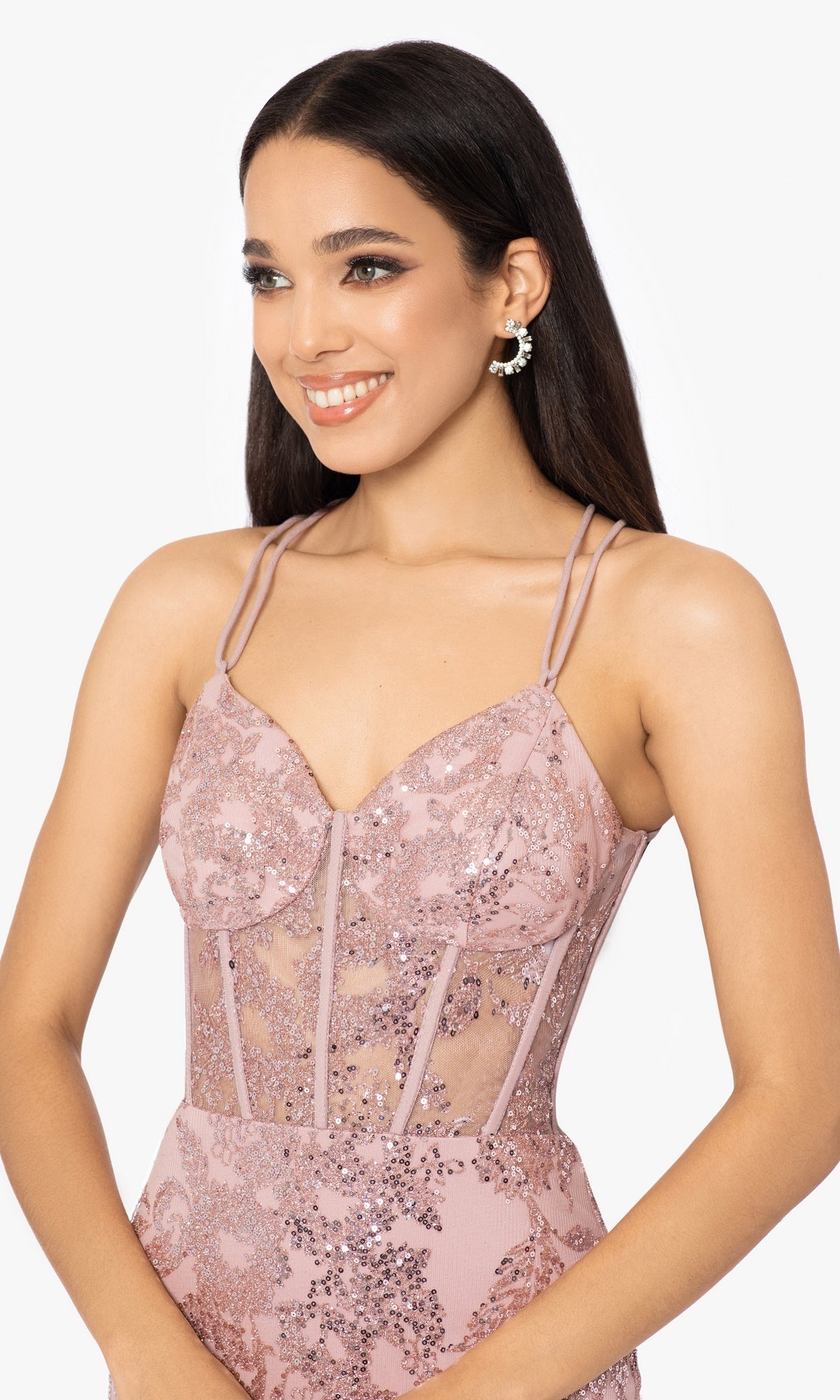 A woman stands smiling against a plain background, wearing the Blondie Nites 3960BN long glitter prom dress—sleeveless, light pink, with thin straps and a corset waist.