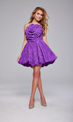 A woman stands in a studio wearing the Jovani 39741 Rosette Short Bubble Hoco Dress in textured purple, featuring ruffled bodice detailing, paired with beige high heels.