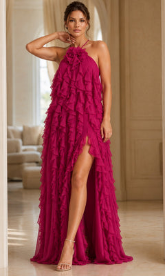 A woman wearing the Long Formal Dress: Jovani 39823 in fuchsia, a sleeveless gown featuring ruffled details, an elegant A-line silhouette, and a high slit, standing indoors on marble flooring with neutral-colored furniture in the background.
