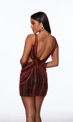 A woman faces away from the camera, modeling the Alyce 40012 short homecoming dress with red and black sequins, a sleeveless design, an open V-back, and large gold earrings.
