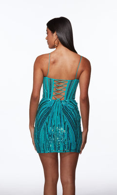 A woman models the Alyce 40016 short homecoming dress, featuring turquoise sequins, spaghetti straps, a corset bodice, and a lace-up back, as she stands facing away from the camera.