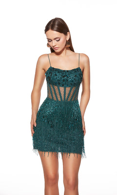A woman stands against a white background wearing the Alyce 40022, a teal short homecoming dress with spaghetti straps, sheer panels, sequin embellishments, and a fitted fringe skirt.