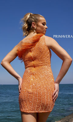A woman stands by the ocean in the One-Shoulder Sequin Party Dress with Feathers 4002, featuring a vibrant orange hue, eye-catching sequins, and a feather-trimmed bodice for standout style.