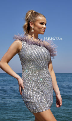 A woman stands by the sea in the One-Shoulder Sequin Party Dress with Feathers 4002 and star-shaped earrings, under a clear blue sky.