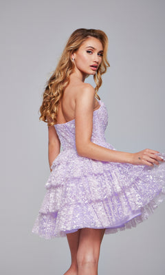 A woman stands against a plain grey background, looking over her shoulder, wearing the Strapless Short Ruffled Hoco Dress: Jovani 40030 in light purple sequins.