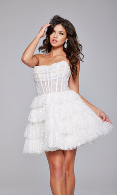 A woman models the Strapless Short Ruffled Hoco Dress: Jovani 40030, featuring a fitted bodice, while posing against a plain grey background.