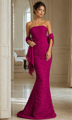 A woman wearing the Jovani 40045 long formal dress in fuchsia with a matching shawl, standing indoors in a spacious, elegant room.