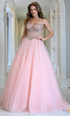 A woman wears a blush Colors Dress 4004, a floor-length prom ball gown featuring an embellished, beaded corset bodice and a full tulle skirt.