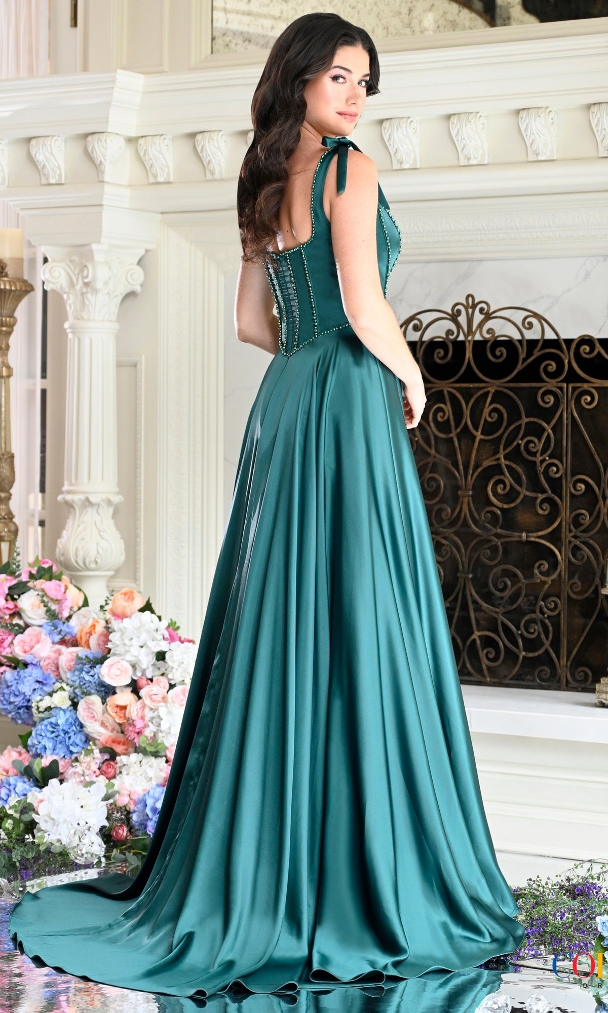 Woman wearing a Long Prom Dress: Colors Dress 4006, a floor-length, emerald green satin gown with a beaded bodice and lace-up back.