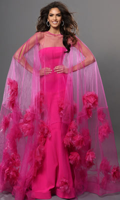 A woman in a vibrant fuchsia Jovani 40092 long formal dress, featuring a sheer matching cape embellished with bold pink floral appliqués, stands against a plain gray background. This exquisite designer gown radiates elegance and sophistication.