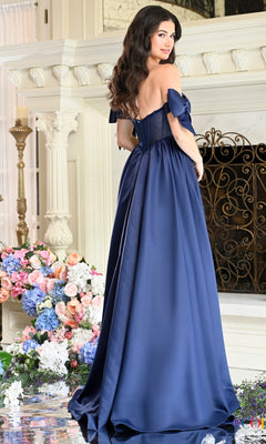 A woman wears a navy blue, off-the-shoulder, A-line Long Prom Dress: Colors Dress 4009 featuring a corset-style bodice and a floor-length silhouette.