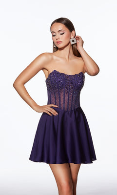Woman in Alyce 40101 Strapless Short Corset Hoco Dress, featuring a bead-embellished bodice and flared skirt, poses with one hand on her hip and the other touching her earring against a white background.