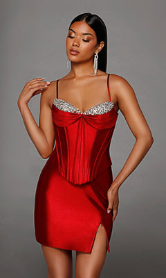 A woman models the Alyce 40163 short homecoming dress in claret satin, featuring a crystal-embellished corset bodice, thin straps, a side slit, and silver chandelier earrings.
