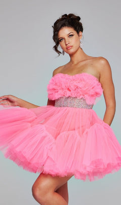 A woman poses against a plain gray background wearing the Jovani 40186 Strapless Short Ruffle Hoco Dress in bright pink tulle, featuring ruffles and a rhinestone belt.
