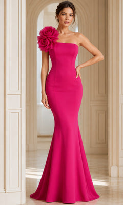 A woman stands in an elegant, light-filled hallway, wearing the Long Formal Dress: Jovani 40201—a floor-length, strapless gown in vibrant fuchsia with a dramatic fabric flower accent on one shoulder.