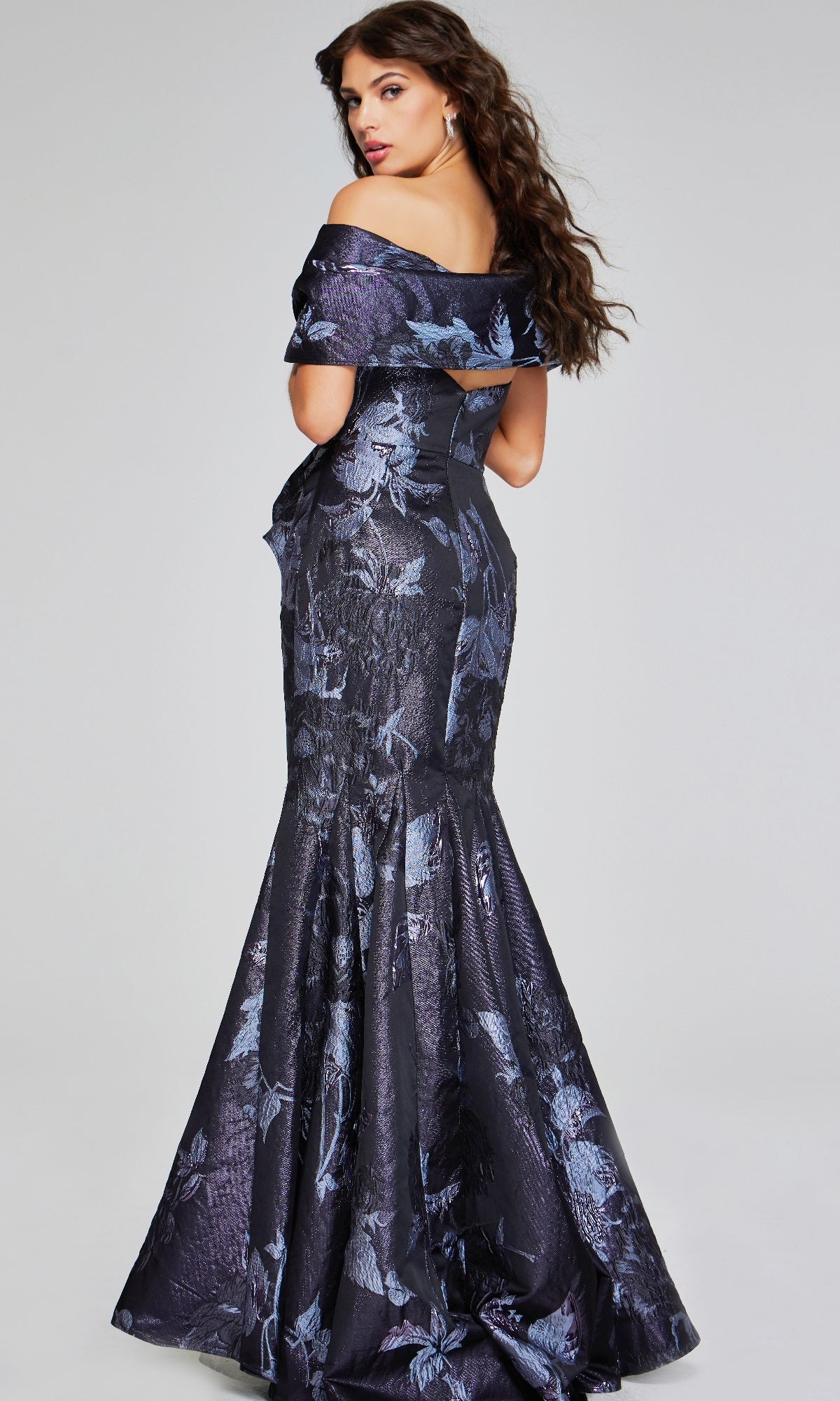 A woman faces away, wearing the Jovani 40309 long formal dress—a strapless mermaid gown with a subtle blue floral print and an elegant, floor-length silhouette.