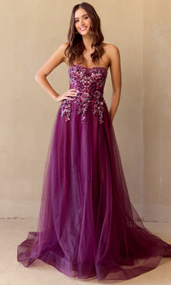 A woman models the Strapless A-Line Prom Gown: Amelia Couture 4031, featuring floral embellishments and a sequin corset bodice, against a plain beige background.
