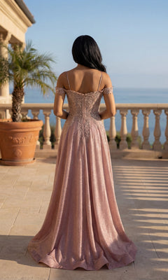 Wearing the Long Prom Dress: Chicas 4031, a woman in a pink glitter a-line gown with an embroidered bodice stands on a terrace overlooking the ocean, with a potted palm tree and stone balustrade behind her.