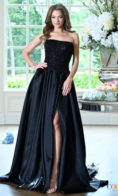 A woman wears a black, strapless Long Prom Dress: Colors Dress 4034 featuring a beaded lace bodice, a floor-length skirt, and a high leg slit.