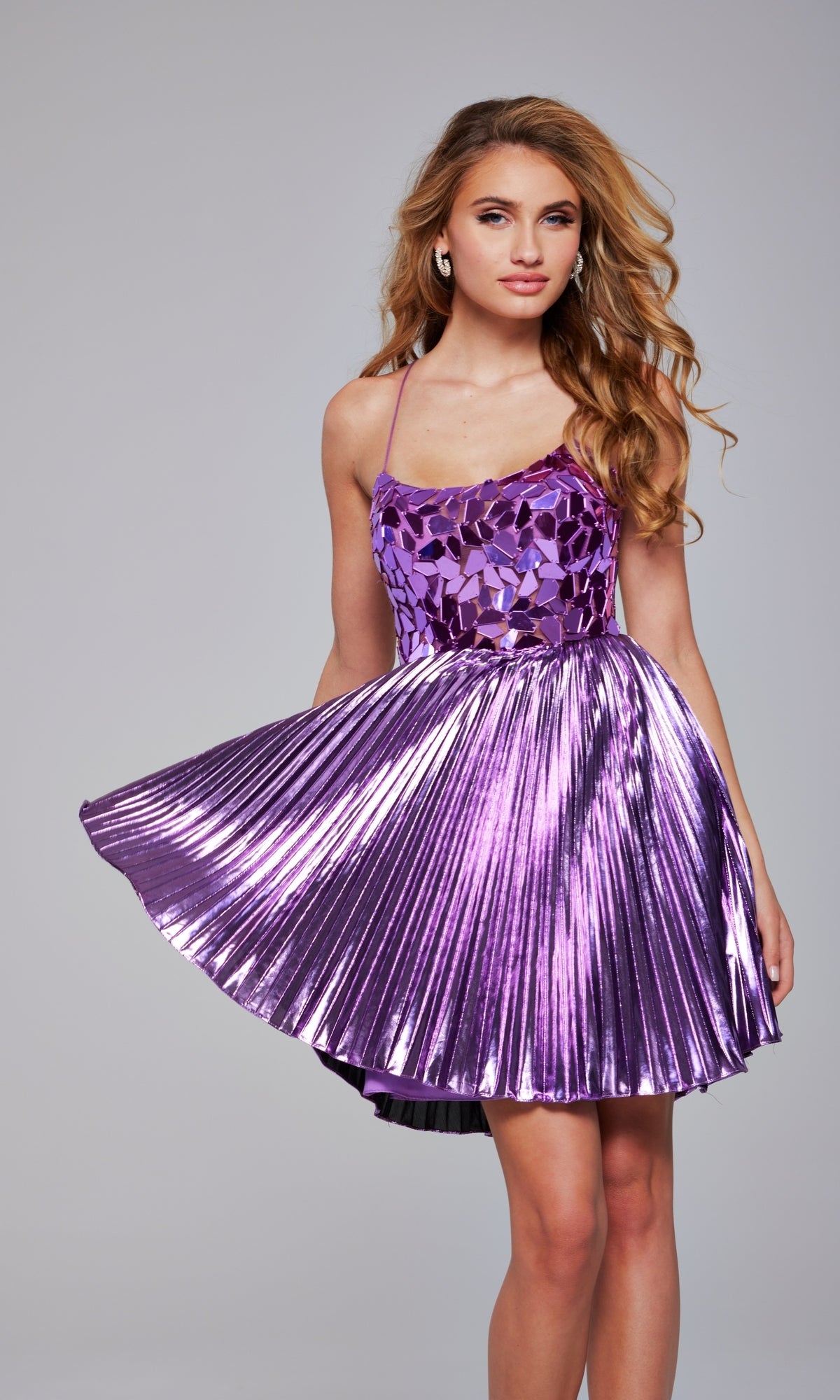 A woman models the Jovani 40350 Short Metallic Pleated Hoco Dress— a sleeveless, shiny purple A-line homecoming dress with mirrored bodice details—standing against a plain gray background.