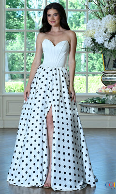 A woman wears a white strapless sweetheart bodice Long Prom Dress: Colors Dress 4036 with a full skirt featuring large black polka dots and a high front slit.