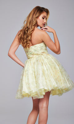 A woman with long, wavy blonde hair wears the Strapless Short Yellow Hoco Dress: Jovani 40374, standing turned away and looking over her shoulder against a plain background.