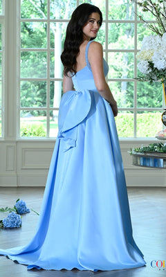 A person wearing the Long Prom Dress: Colors Dress 4037, a floor-length, light blue satin A-line gown with beaded straps and a large bow at the back.