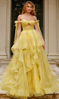 A woman stands on stone steps in front of ornate doors and columns, wearing the Long Prom Dress: Jovani 40400—a yellow off-the-shoulder gown with a layered ball-gown skirt and sheer detailing.