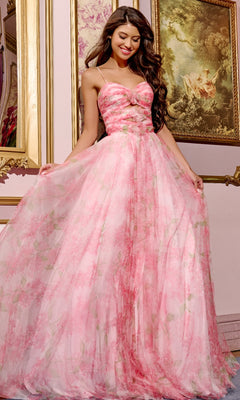 A woman in a strapless red floral-print Jovani 40402 prom dress stands indoors, smiling as she holds out the skirt of her a-line gown. Ornate framed paintings are displayed on the wall behind her.