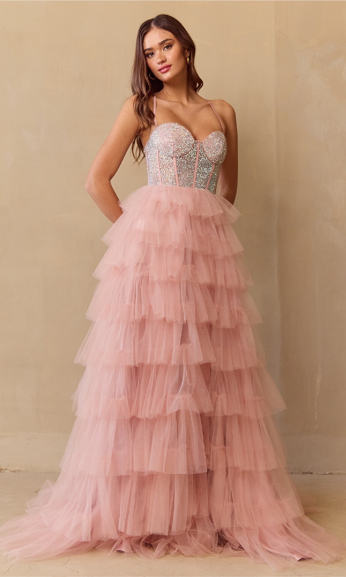 Woman wearing a blush pink tiered dress with a beaded top against a beige background
