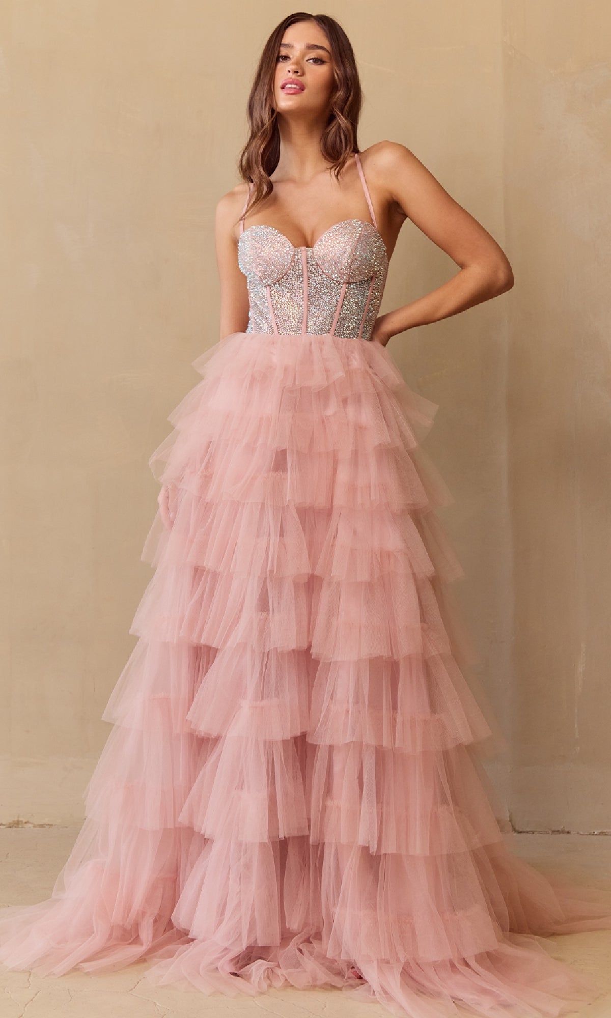 Woman wearing a blush pink tiered ball gown dress with a beige background