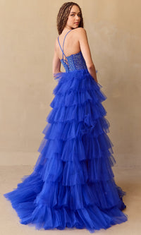 Woman modeling the back of a royal blue tiered ball gown with an intricate top on a beige background