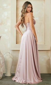 Woman modeling the back of a pink strapless gown in a room with decorative elements.