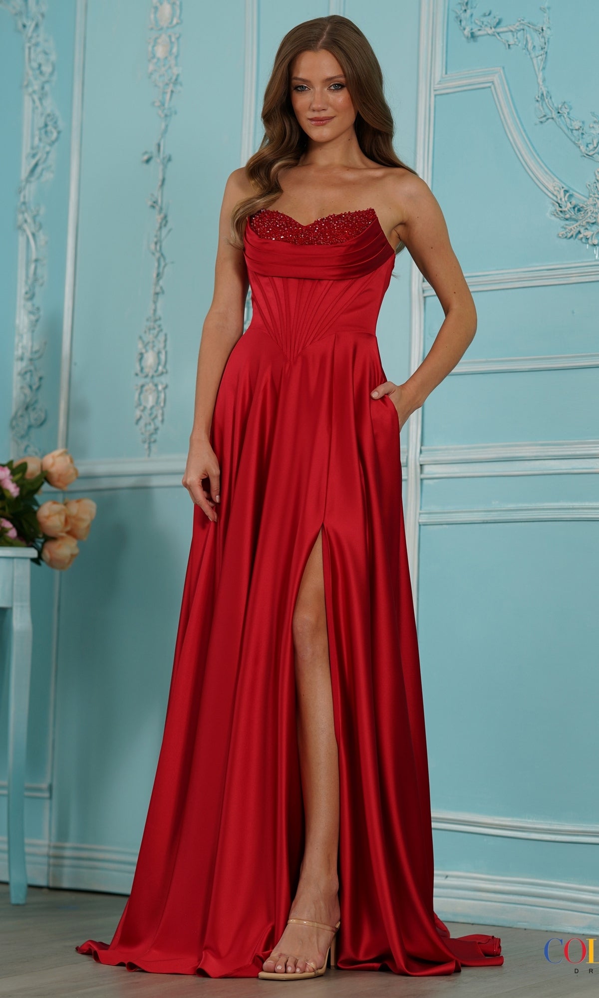 Long Prom Dress: Colors Dress 4057, a red strapless floor-length satin gown with a rhinestone neckline, corset-style waist, and high leg slit.