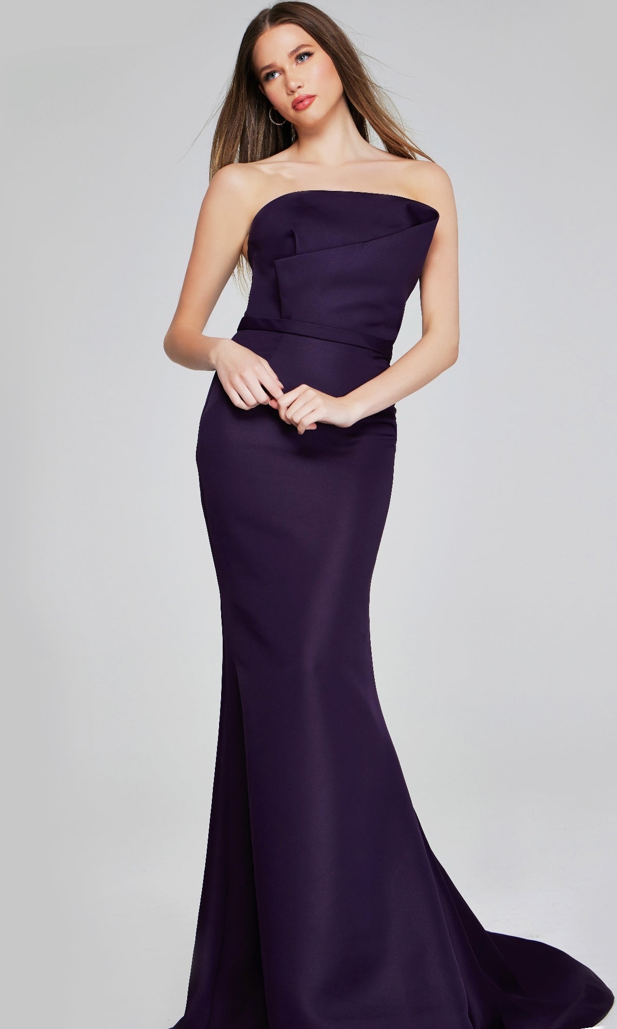 A woman stands against a plain light gray background wearing the Jovani 40598 long formal dress—a strapless, dark purple satin evening gown with a fitted, floor-length mermaid silhouette.