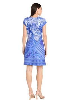 A woman faces away wearing the R&M Richards 4061 Short Blue Print Party Dress with nude heeled sandals against a white background—the ideal spring and summer party dress for any occasion.