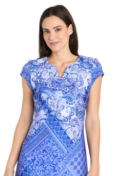Woman with long dark hair wears the R&M Richards 4061 Short Blue Print Party Dress, featuring cap sleeves. She stands facing the camera with a neutral expression—a stylish choice for spring and summer occasions.
