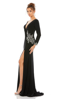 A woman models the Long Formal Dress 41016 by Mac Duggal—a black gown with long sleeves, a thigh-high slit, and silver floral embellishments—against a white background.